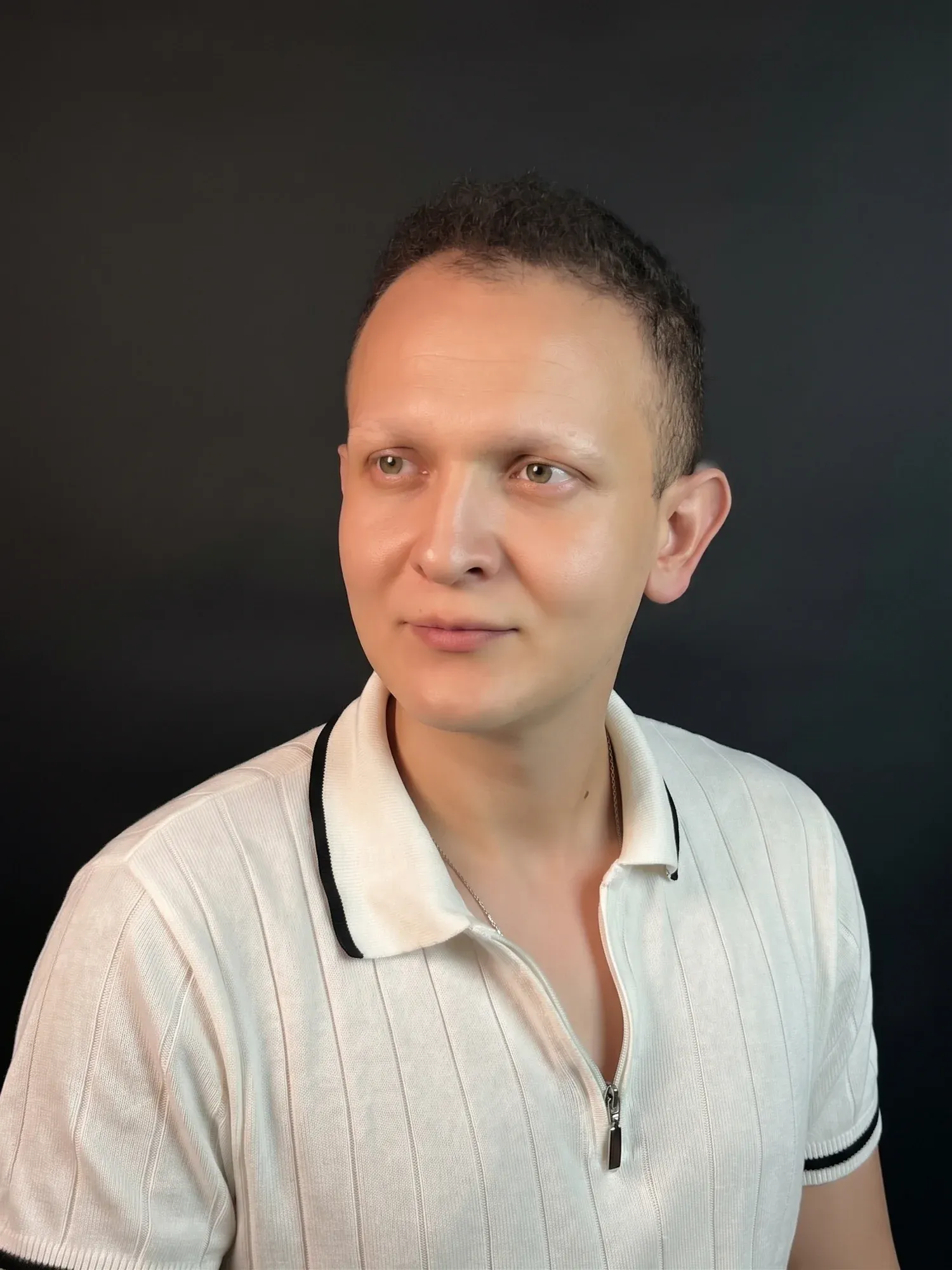 Koyu bir fonun önünde, beyaz yakalı tişörtüyle Furkan Bekdik’in portresi.
